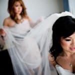 A bride puts on her veil with the help of her maid of honor photo taken by Portland, Oregon wedding photographers.