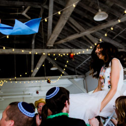 Would you like to attend a Jewish wedding in an airplane hanger? Or a wedding where the bride’s hand drawn cartoon animals serve as centerpieces? How about a wedding where the groom wore a green suit? Yes, green. And while we’re at it, would you like to eat delicious kosher fish tacos from the only kosher caterer in the city? Or would you like to be at a wedding with the only klezmer band within a 300 mile radius who drove 3 hours to kick off the party? How about wearing a custom made kippah while playing finger puppets with your ceremony seat mates? Um, the answer to these questions is yes, yes, yes, yes, yes and yes. We’re actually sad you all couldn’t be at Brooke and Boaz’s incredibly fun, inventive and unique Jewish wedding that we had the privilege and honor to document. We have know Boaz, creator of the Pedal Powered Talk Show, for a long time and we were overjoyed when he and Brooke were engaged. Brooke, creator of the New York Times best seller Sad Animal Facts, is the cheese to Boaz’s macaroni. Together they are the creators of another bestseller, the It’s Different Every Day calendar series and it’s perfectly OK to stop and google them now. Brooke and Boaz are a dynamic pair. Smart, talented, funny as heck and also two of the nicest people you will ever meet. I know that’s thrown around a lot but truly, we stand behind that statement. The nicest. Brooke and Boaz threw a laid back yet seamlessly organized traditional Jewish wedding inside of an airplane hangar in Vancouver, Washington. That was a first for us and the hangar created such an expansive canvas for which to create truly special photographs. Especially when we suggested Brooke and Boaz get ready in the hangar’s air museum and of course, they happily obliged. Brooke and Boaz incorporated family and friends to help in the ceremony and in creating the unique details that comprised their event. It began with flower girls throwing confetti instead of flowers and Brooke’s cousins sons sweeping the confetti with tiny push brooms. Boaz and Brooke’s family performed readings while close friends held the chuppah raised above them. A favorite moment for all of us was when Brooke and Boaz chose to break the glass and run, not walk, out of the ceremony. That moment was a kick off to a party (hello klezmer band!) that had us all smiling, laughing and drinking slushies until the sun went down. Words cannot express the gratitude we have towards not only knowing this couple but being given the honor to capture their wedding day. And if you’ve read this far, we encourage you to hop on over to the only Jewish wedding blog, Smashing the Glass, for a special feature of Brooke and Boaz’s wedding plus more photos from the big day. Mazel Tov, Brooke & Boaz!