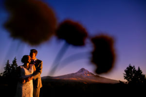 Awesome creative portrait of bride and groom with Mt. Hood in background taken at Mt. Hood Organic Farms in Hood River, Oregon by Stark Photography.
