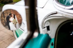 Cool creative portrait of the bride and groom kissing in the reflection of a rearview mirror on their get-away car outside of Wedding party portraits outside Holy Trinity Greek Orthodox Cathedral in Portland Oregon.