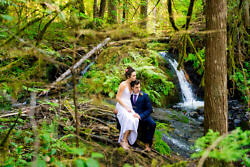 bride and groom pose for a photographer in front of waterfalls at camp Colton