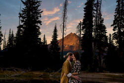 Man and woman snuggling in front of Mt. Bachelor at sunset during golden hour