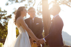 Wedding couple exchange vows in wedding ceremony with warm light around them.
