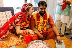 bride and groom laughing with hands in milk for post Indian wedding tradition