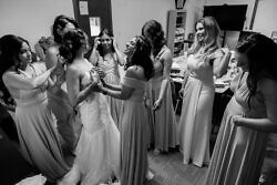 bride surrounded by bridesmaids while putting on her dress before a church wedding ceremony in Portland