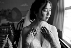 bride touches neck while posing for a window lit portrait before her wedding