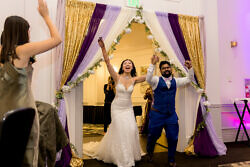 bride and groom lift hands in the air when entering their wedding reception