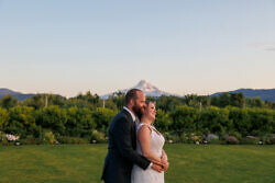 newly married couple poses in front of mt hood at sunset